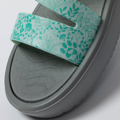Gray sandal with a green floral strap on a light gray background