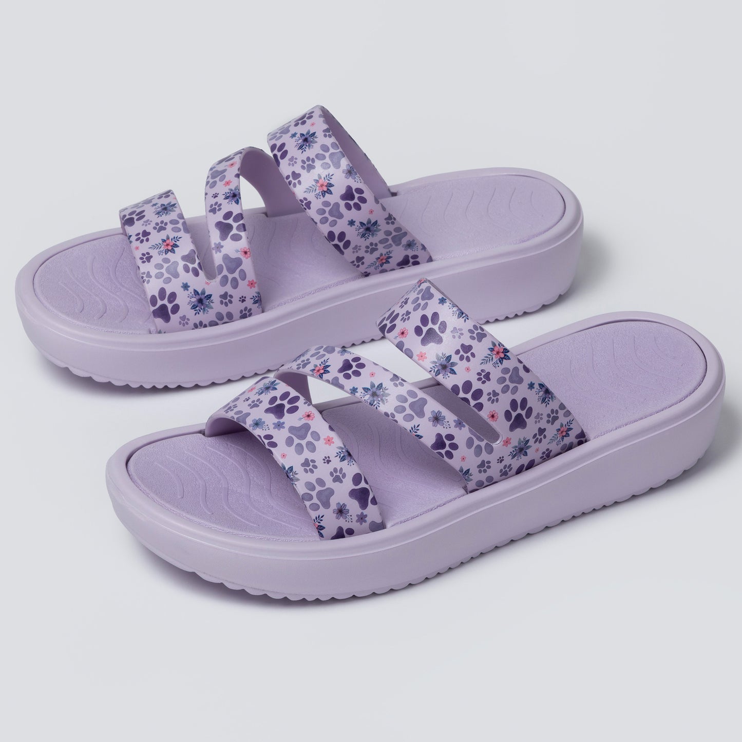 Pair of purple sandals with floral pattern on a light gray background