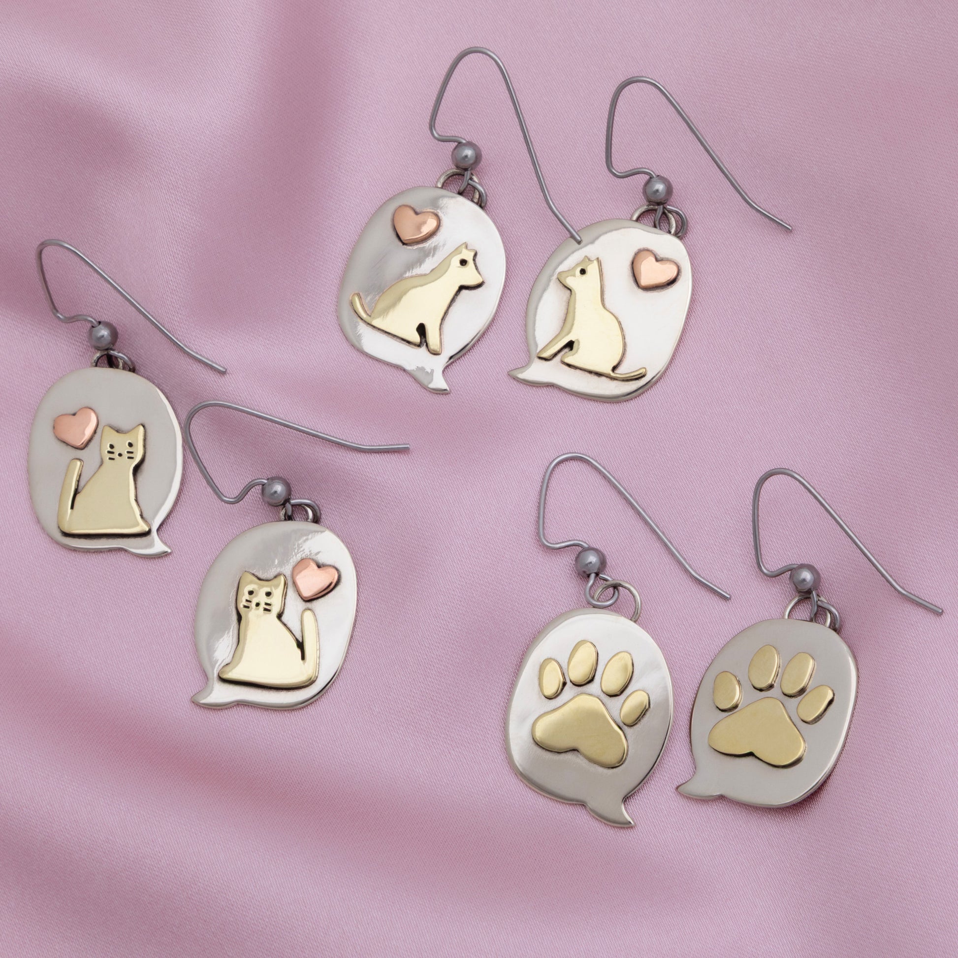Pairs of earrings with cat and dog illustrations on a pink background