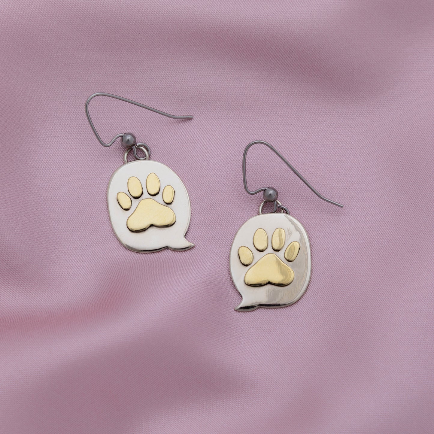 Paw print earrings on a pink fabric background