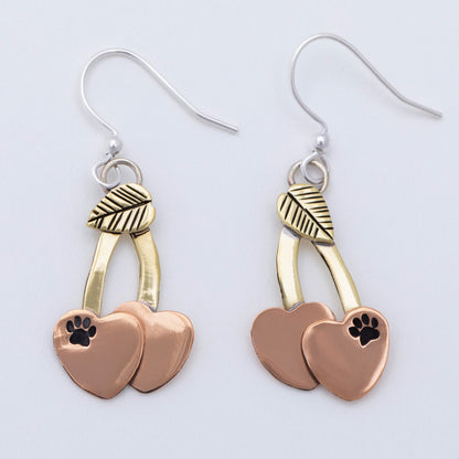 Cherry shaped mixed metal earrings with a small paw print, on a white background.