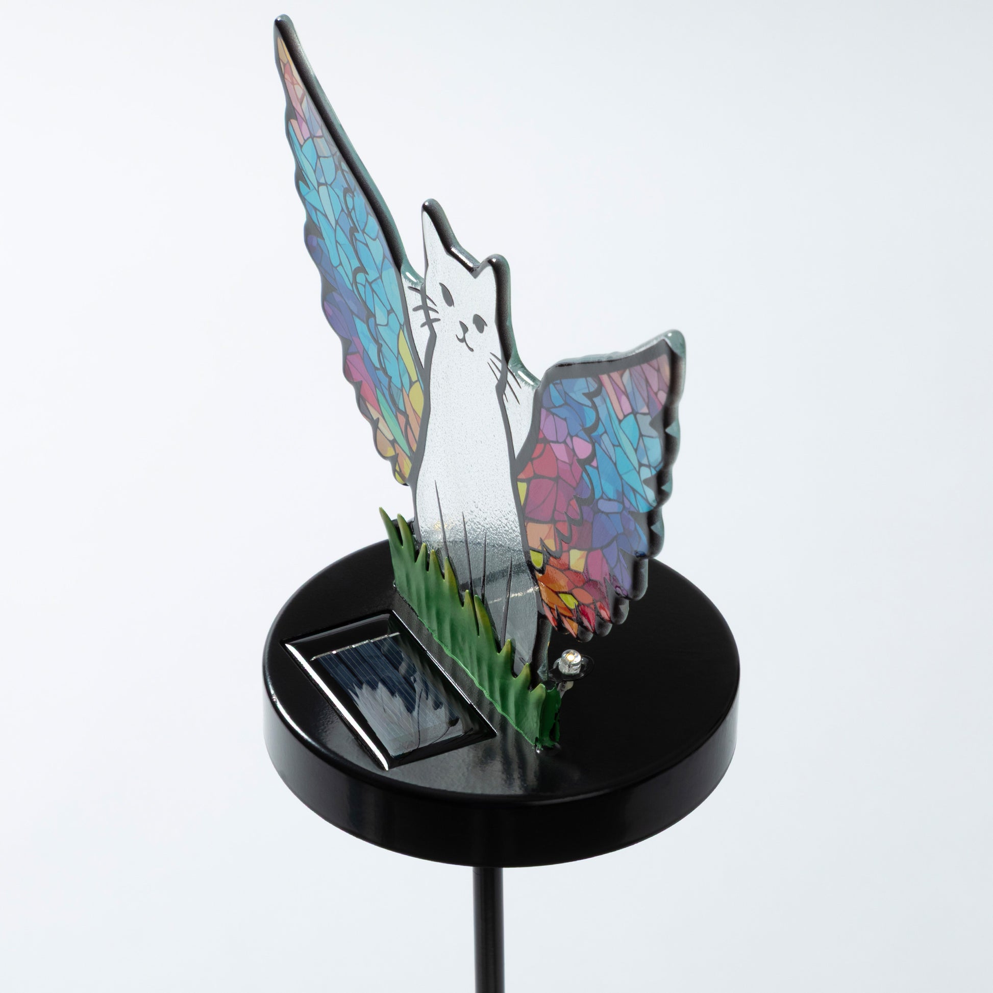 Cat silhouette with mosaic angel wings on a garden stake with a small solar panel, against a white background.