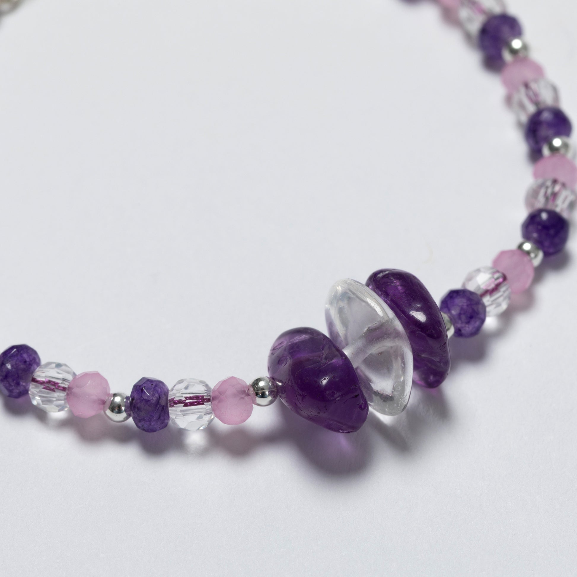 Necklace with purple, pink, and clear beads on a white background