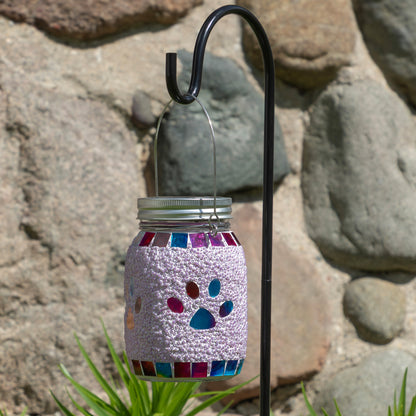 Decorative mason jar with colorful paw prints hanging against a stone wall.