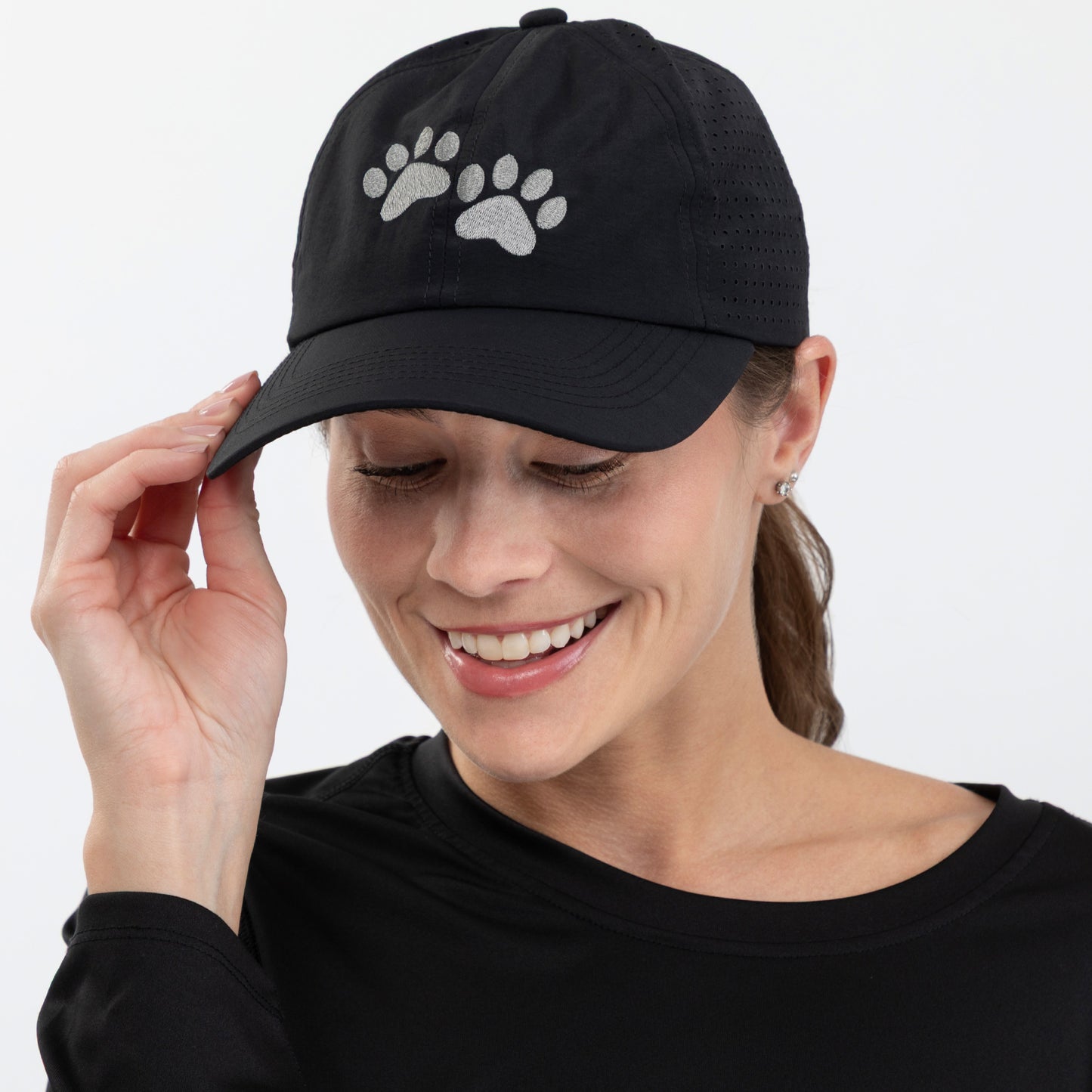 Woman wearing a black cap with paw prints on a white background