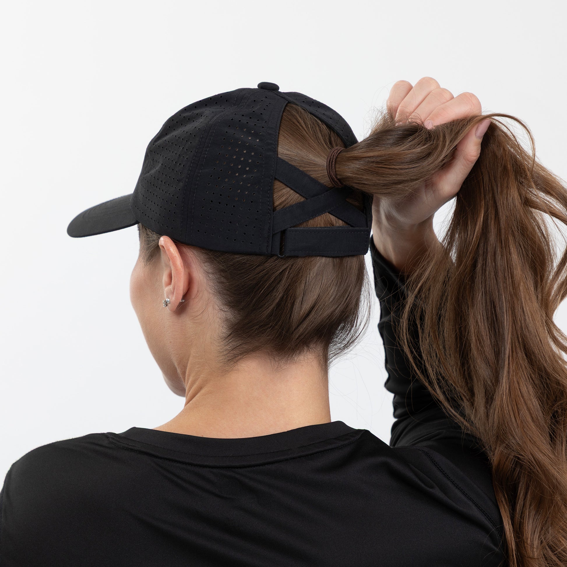 Person wearing a black cap and black shirt with long hair tied back, on a white background