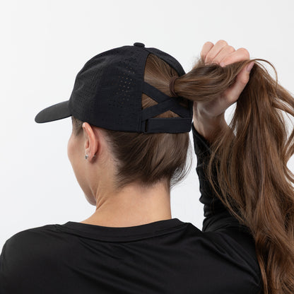 Person wearing a black cap and black shirt with long hair tied back, on a white background