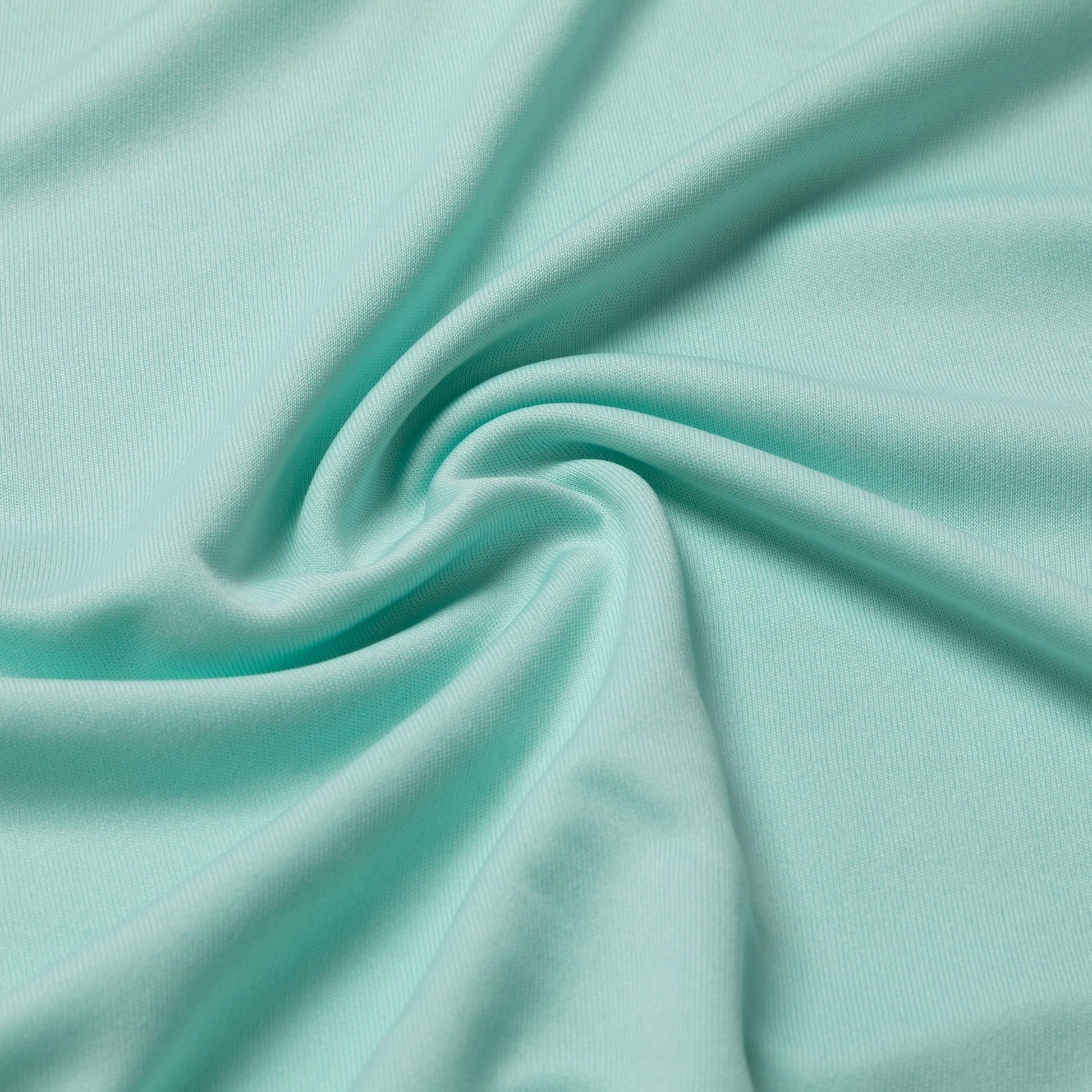 A close-up of mint green fabric with soft folds and a smooth texture, filling the entire frame.