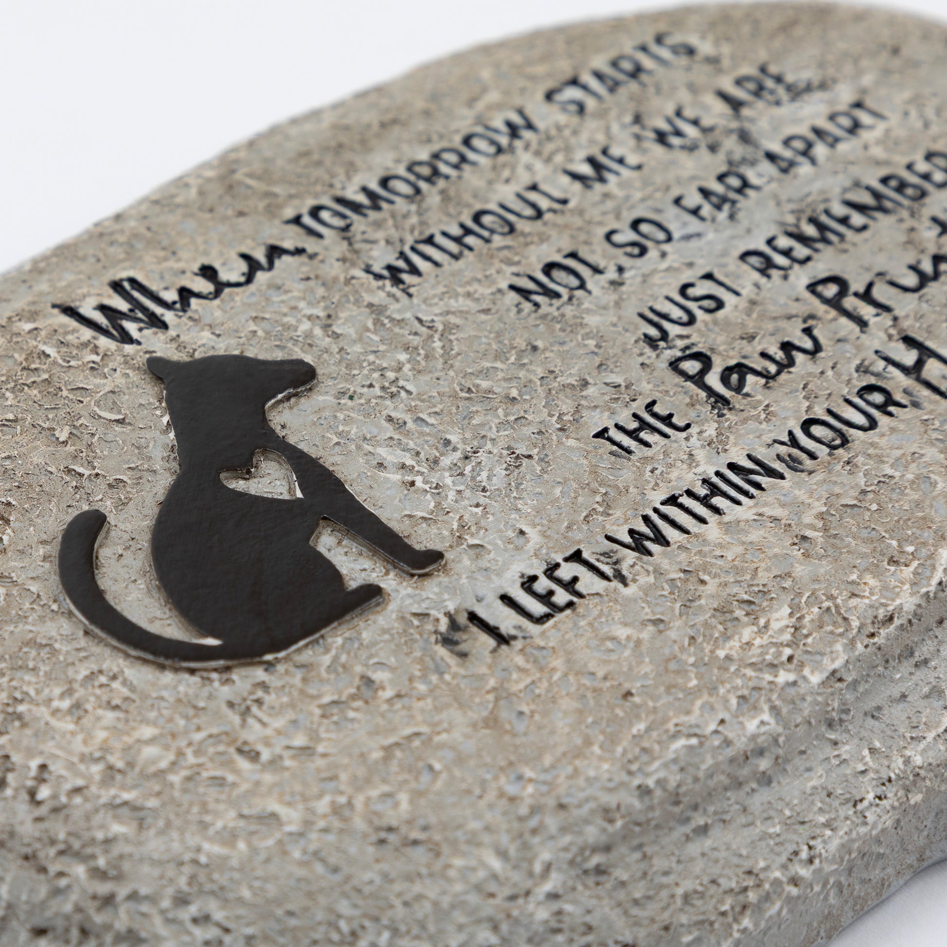 Close up of polyresin garden stone with a dog silhouette and engraved text on a white background