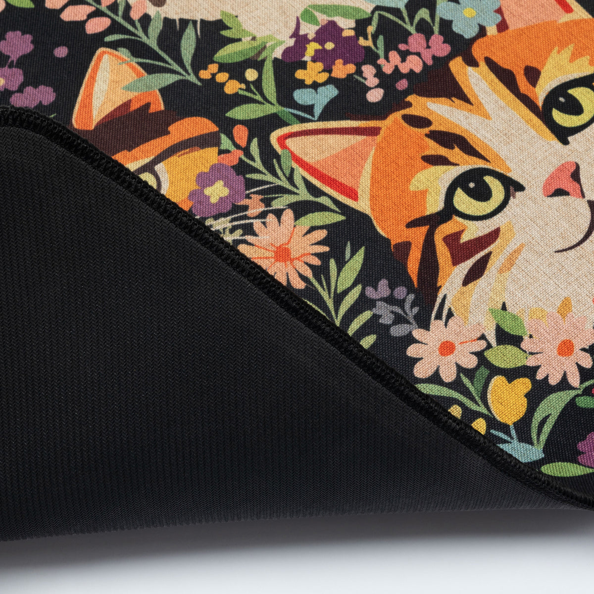 Close-up of a black floor runner with a colorful floral and cat print on top, folded over to show the black fabric underside.