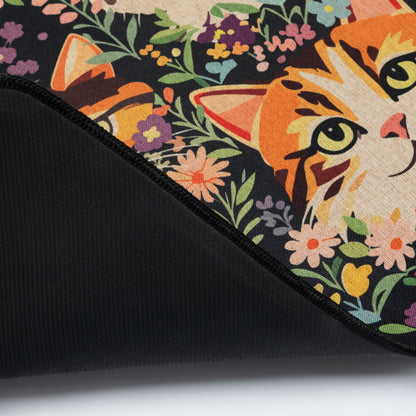 Close-up of a black floor runner with a colorful floral and cat print on top, folded over to show the black fabric underside.