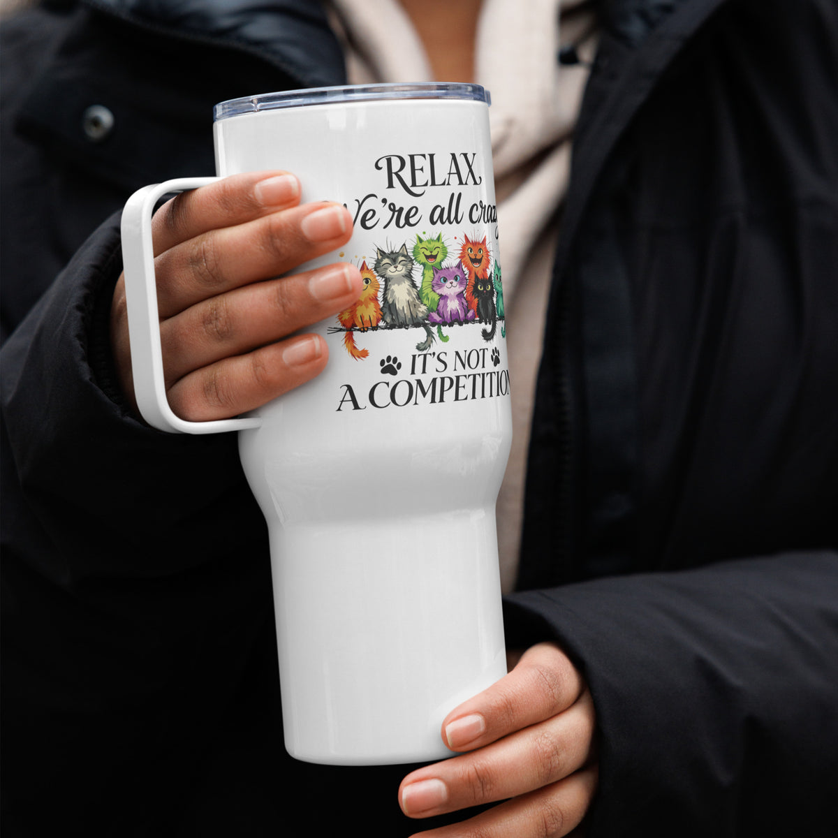 Person holding a white tumbler with an cat design and text.