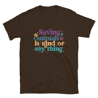 Brown shirt that reads Saving Animals is kind of my Thing with several paw print and sparkle images in a purple, yellow and blue font.