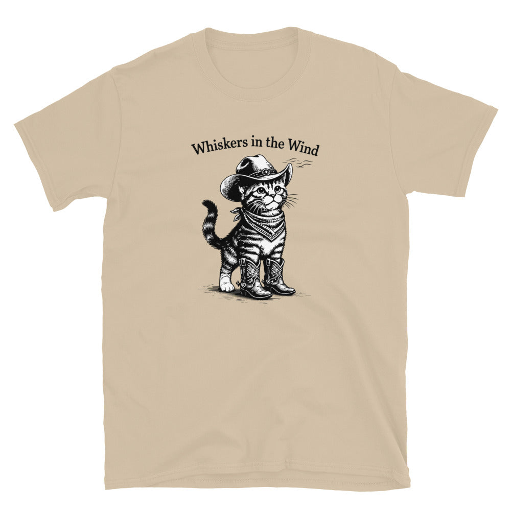 Beige t-shirt with a graphic of a cat wearing a cowboy hat and boots, and the text 'Whiskers in the Wind'.