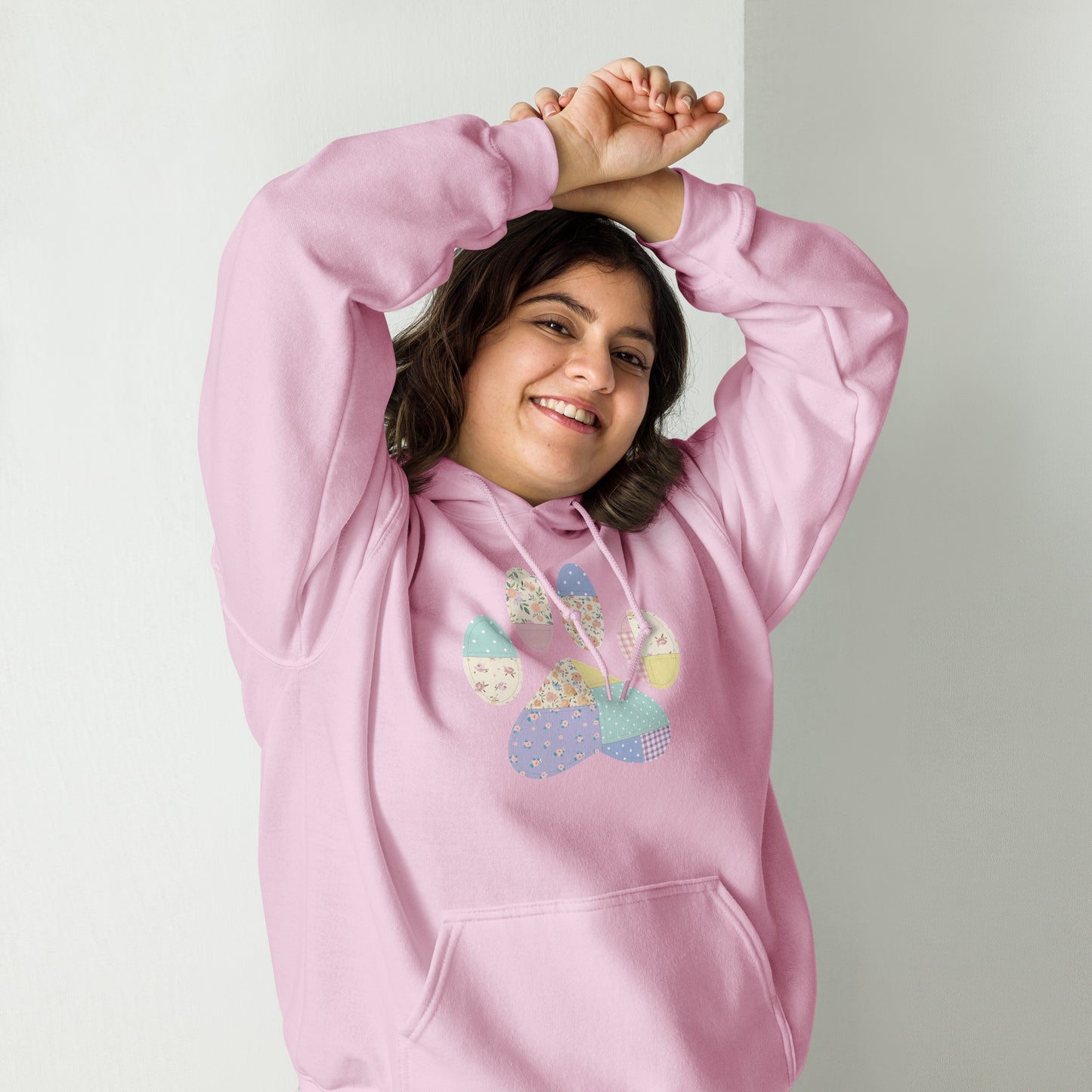 Person wearing a pink hoodie with colorful paw print design on a plain background